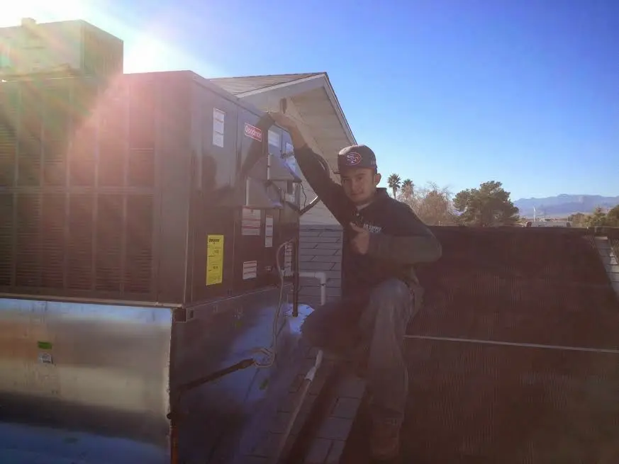 HVAC technician performing Air Duct Repair on a rooftop unit in Byron